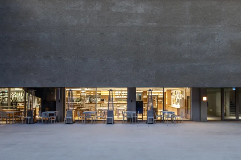 Glass-fronted venue with outdoor seating under a dark wall